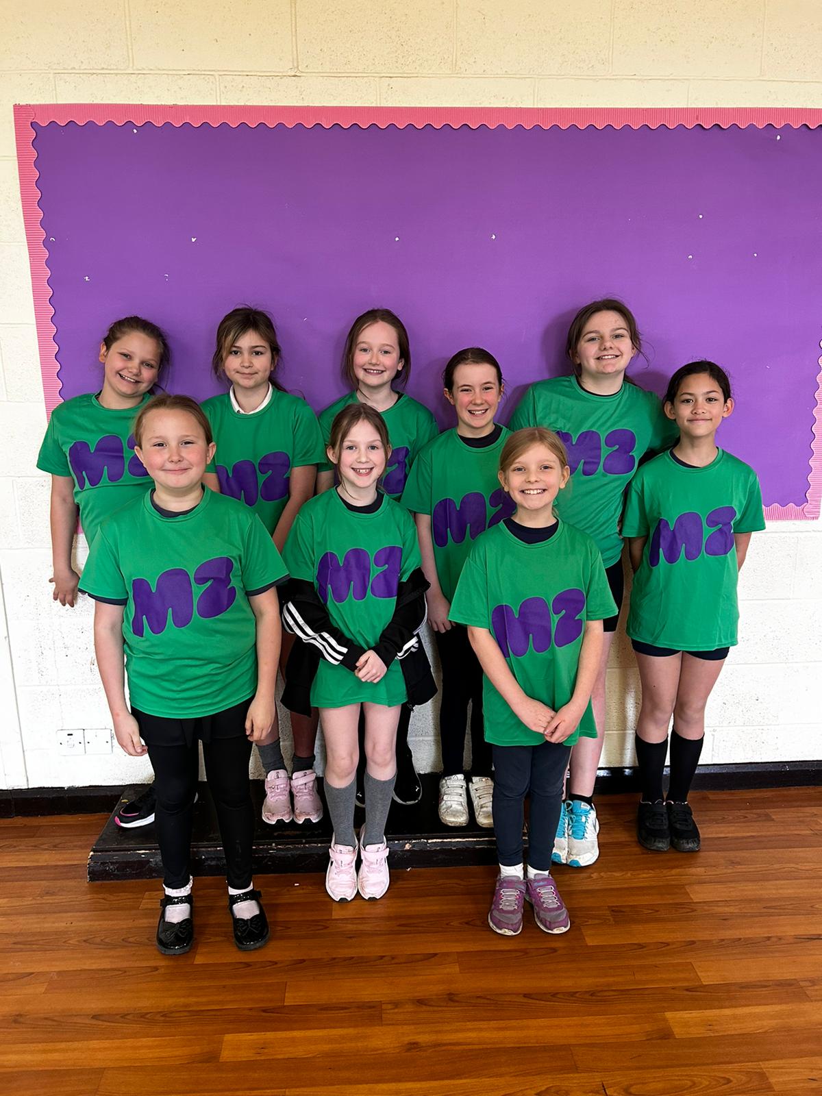 A group of girls wearing green M2 T-shirts